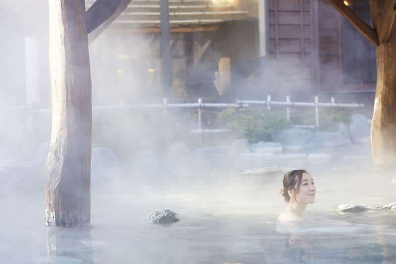 Woman relaxing in an onsen surrounded by steam
