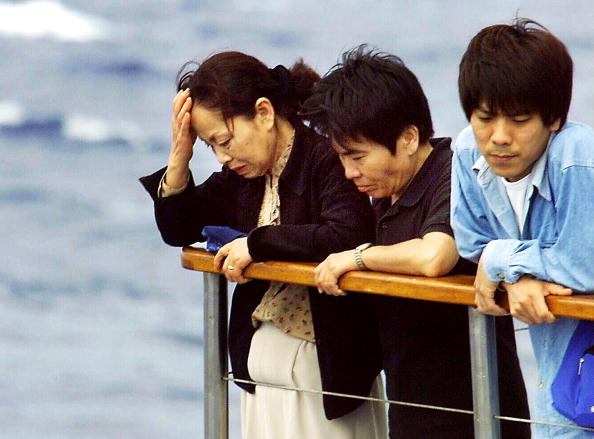 HONOLULU, UNITED STATES: Relatives of the Ehime-maru victims gaze at the surface of the sea off Honolulu in Hawaii 04 March 2001 as they throw flowers into the sea at the spot where the US submarine Greeneville collided with a Japanese fishing-school boat.