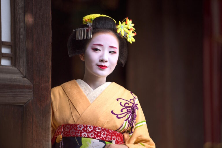 KYOTO, JAPAN - NOVEMBER 28, 2015: A woman dressed as a traditional Maiko looks out of a temple doorway.