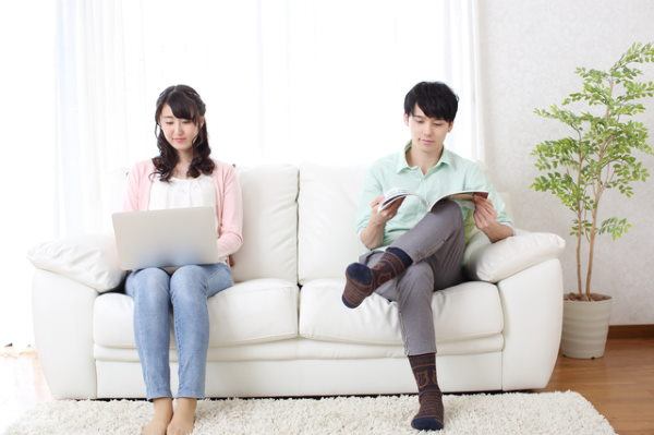 Couple sitting separately on a couch - separate spousal surnames story