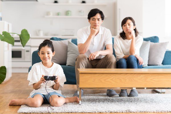 Girl playing video games while skeptical parents look on