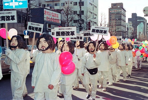 TOKYO, JAPAN - JANUARY 27: Japanese doomsday cult Aum Shinrikyo members wearing their guru Shoko Asahara's masks parade on January 27, 1990 in Tokyo, Japan.