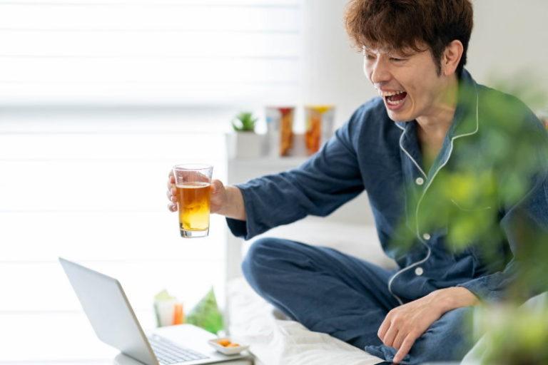 Man doing virtual happy hour (オンライン飲み会) at home