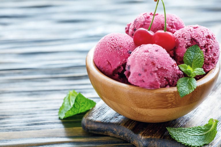 Bowl of homemade cherry ice cream on old wooden table, selective focus.