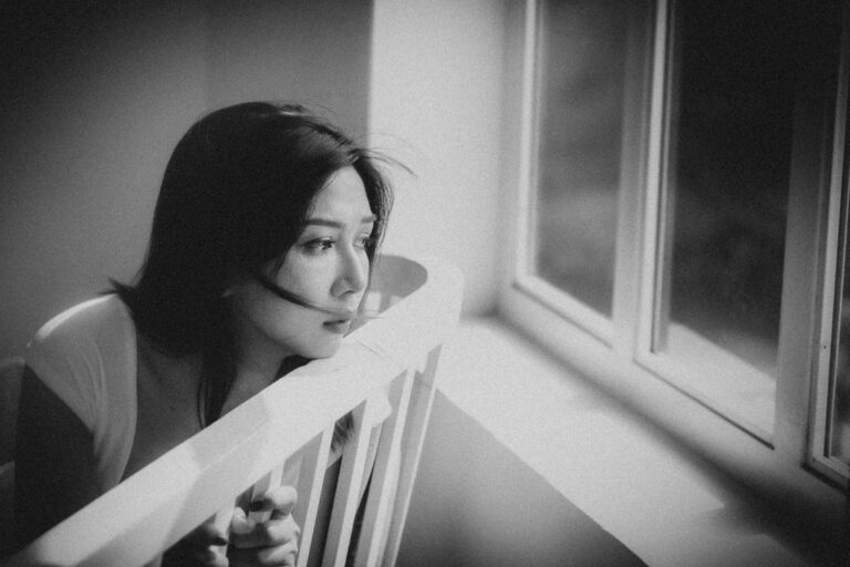 woman at home looking sadly out window
