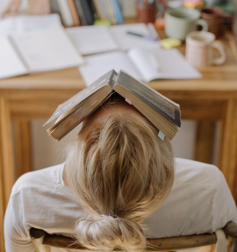 Image of tired student with book over their face