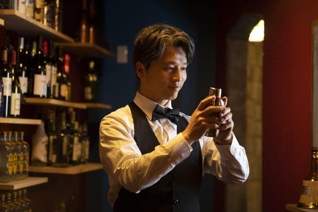 A Japanese bartender prepares a cocktail in a cobbler shaker.