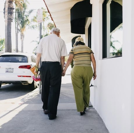 an elderly couple walking towards a car
