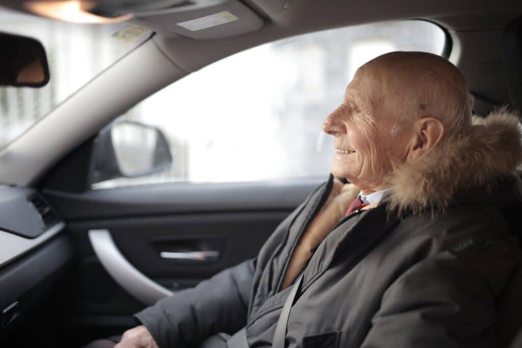 an elderly man sits in a car passenger seat