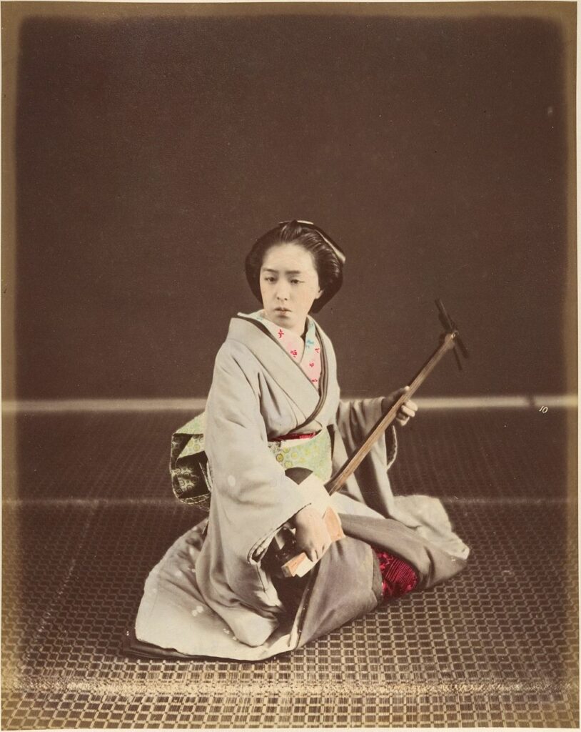 A Tokyo geisha plays the shamisen in a colorized photograph from the 1870s.