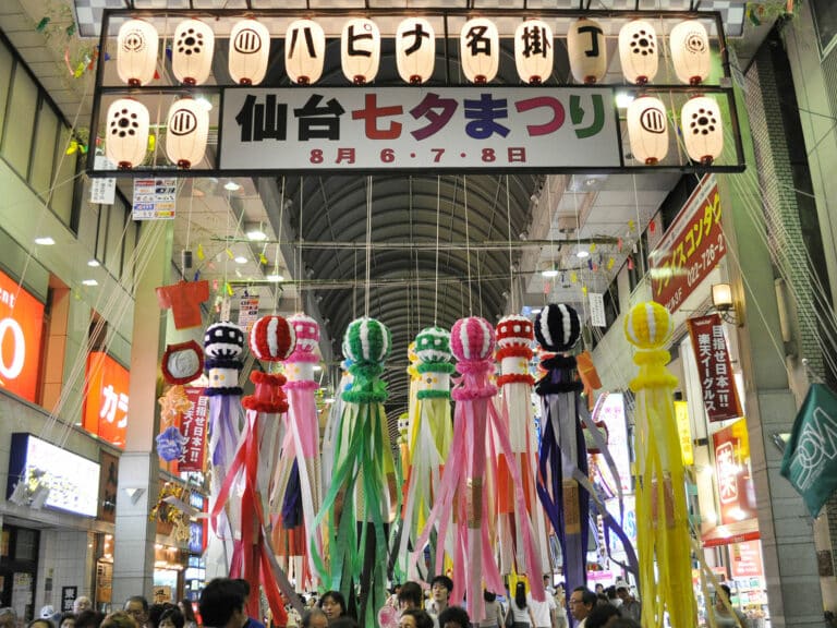 Sendai Tanabata decorations hanging from a sign in a covered shopping area.