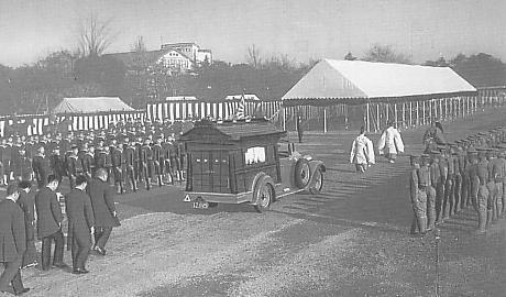 A hearse resembling a shinto shrine drives down pare grounds surrounded on either side by soldiers standing at attention during the 1940 state funeral of Saionji Kinmochi.