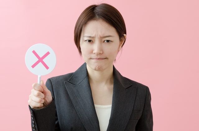 Woman holding up a sign with an X