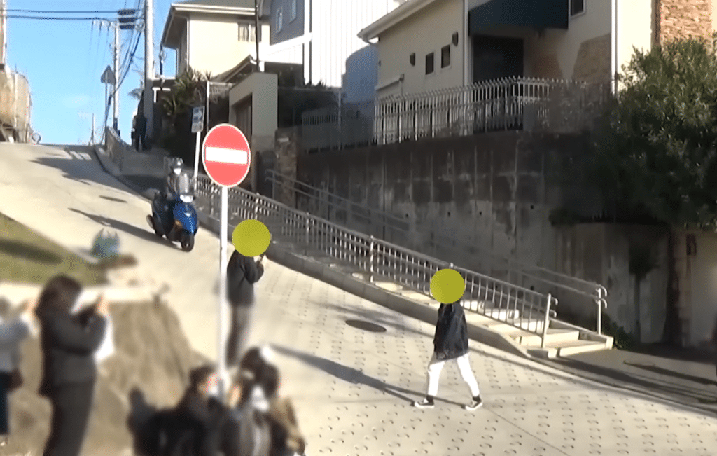Motorcyle trying to get past two tourists standing in the middle of the street.
