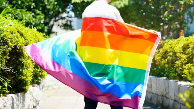 Person wrapped in LGBTQ flag