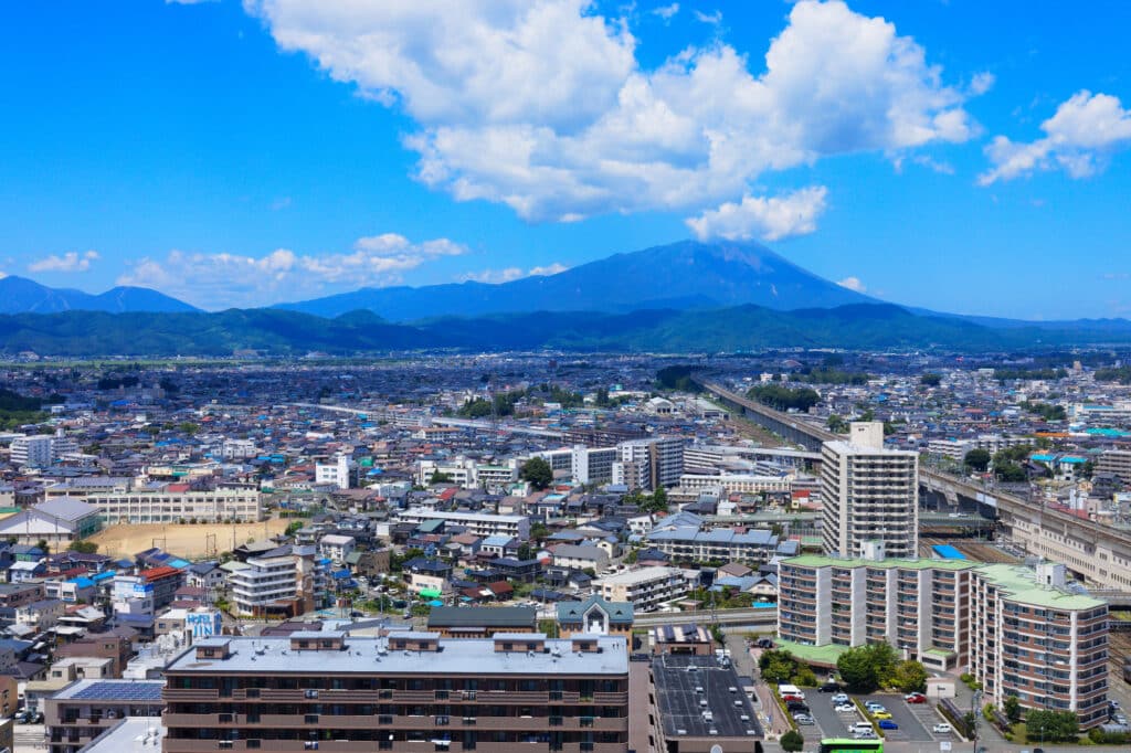 A cityscape of Morioka, with mountains and blue sky in background. Morioka is accessible by JR Pass and JR East Pass.