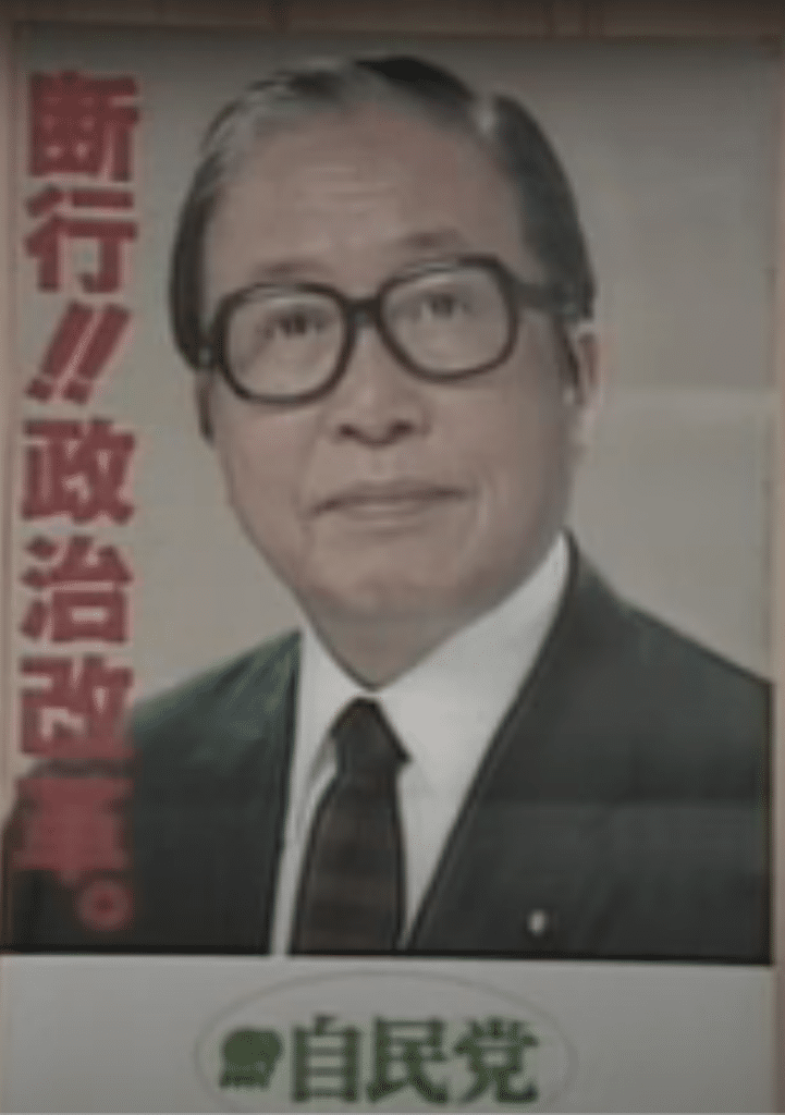 A Japanese election poster featuring Prime Minister Uno Sosuke, wearing black rimmed glasses, a suit, and the recognizable white streak in his hair.