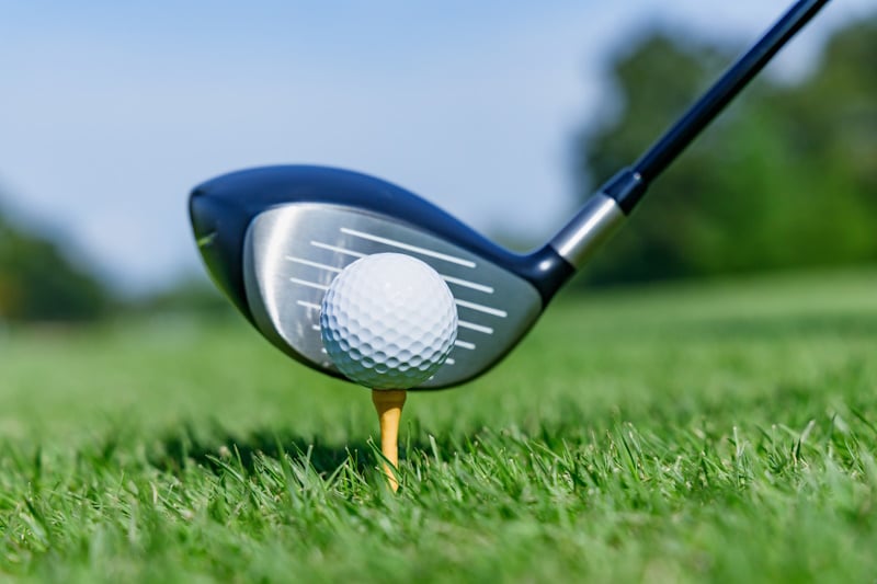 Golf club about to hit golf ball