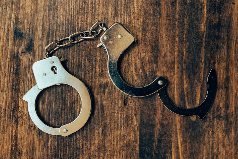 Uncuffed, open hand cuffs on wooden police office desk, top view