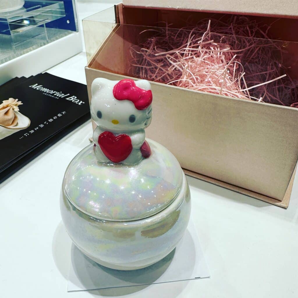 Pearlescent, round urn with Hello Kitty on top at ENDEX.