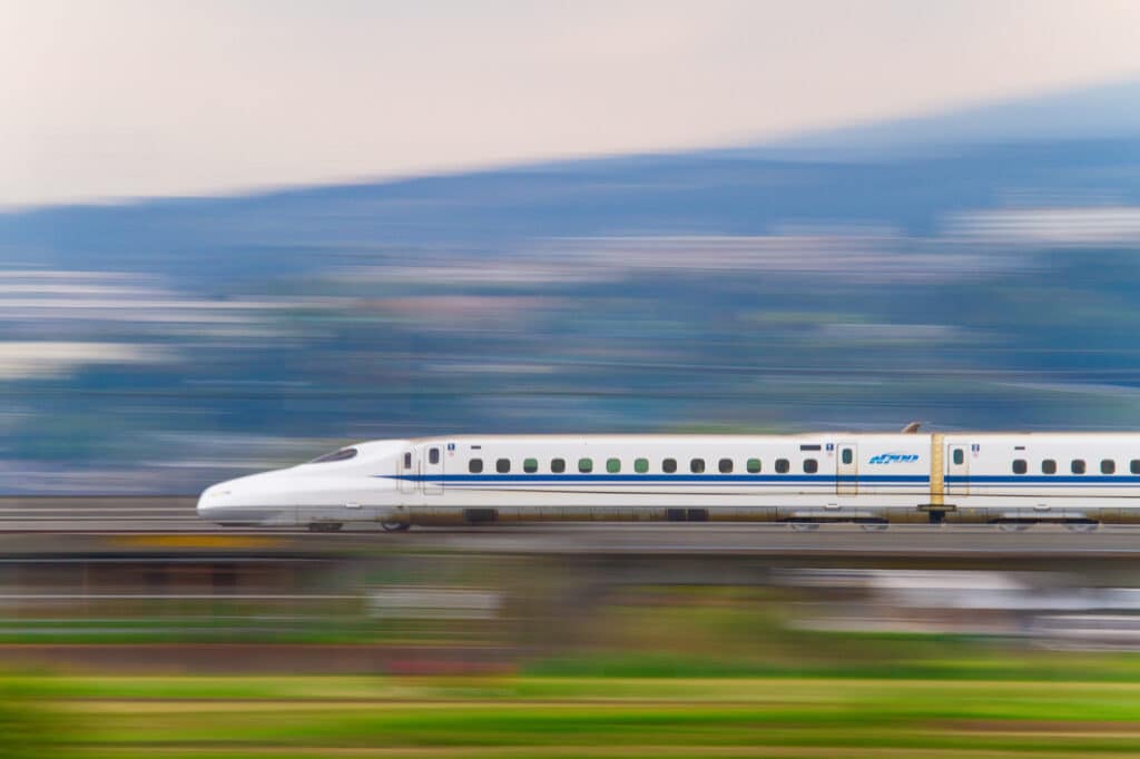 The Nozomi shinkansen zooms past a blurred background.