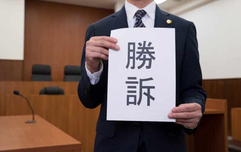 Man holding up "legal victory" sign (勝訴; shouso)