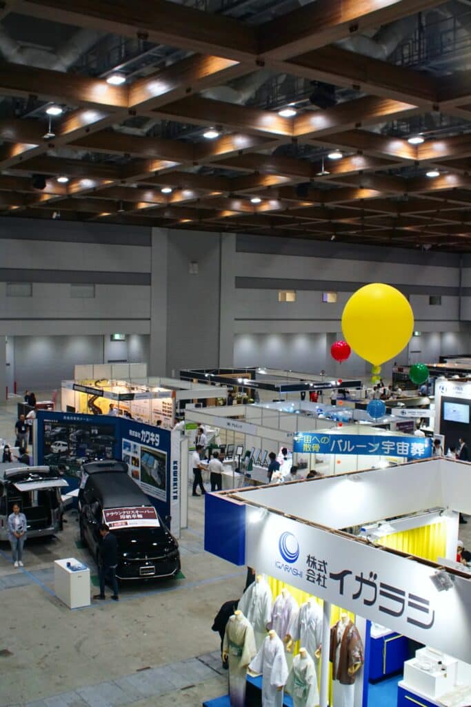 The high-ceilinged show halls of ENDEX with multiple booths showing kimono, hearses, and more.