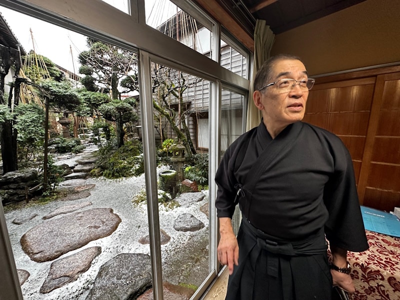 Nagamachi Samurai District, Kanazawa. Teacher holding sword while standing next to window.