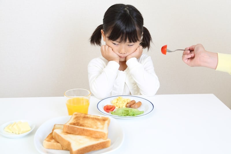 Girl refusing to eat a tomato