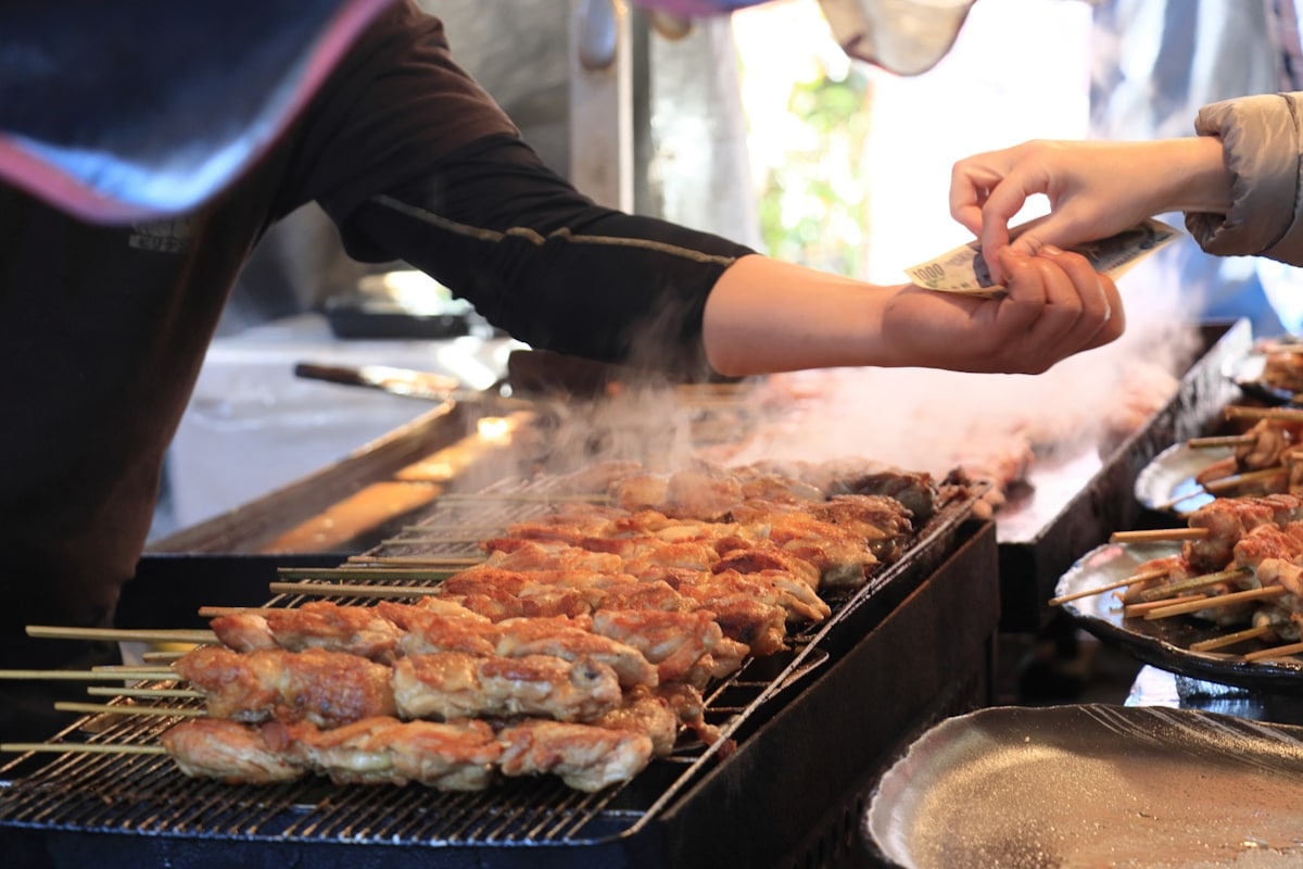 Person paying for kushiyaki - Japan two-tier tourist charging system