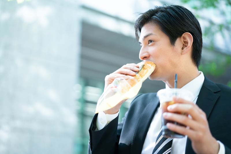 Man drinking iced coffee and eating a sandwich
