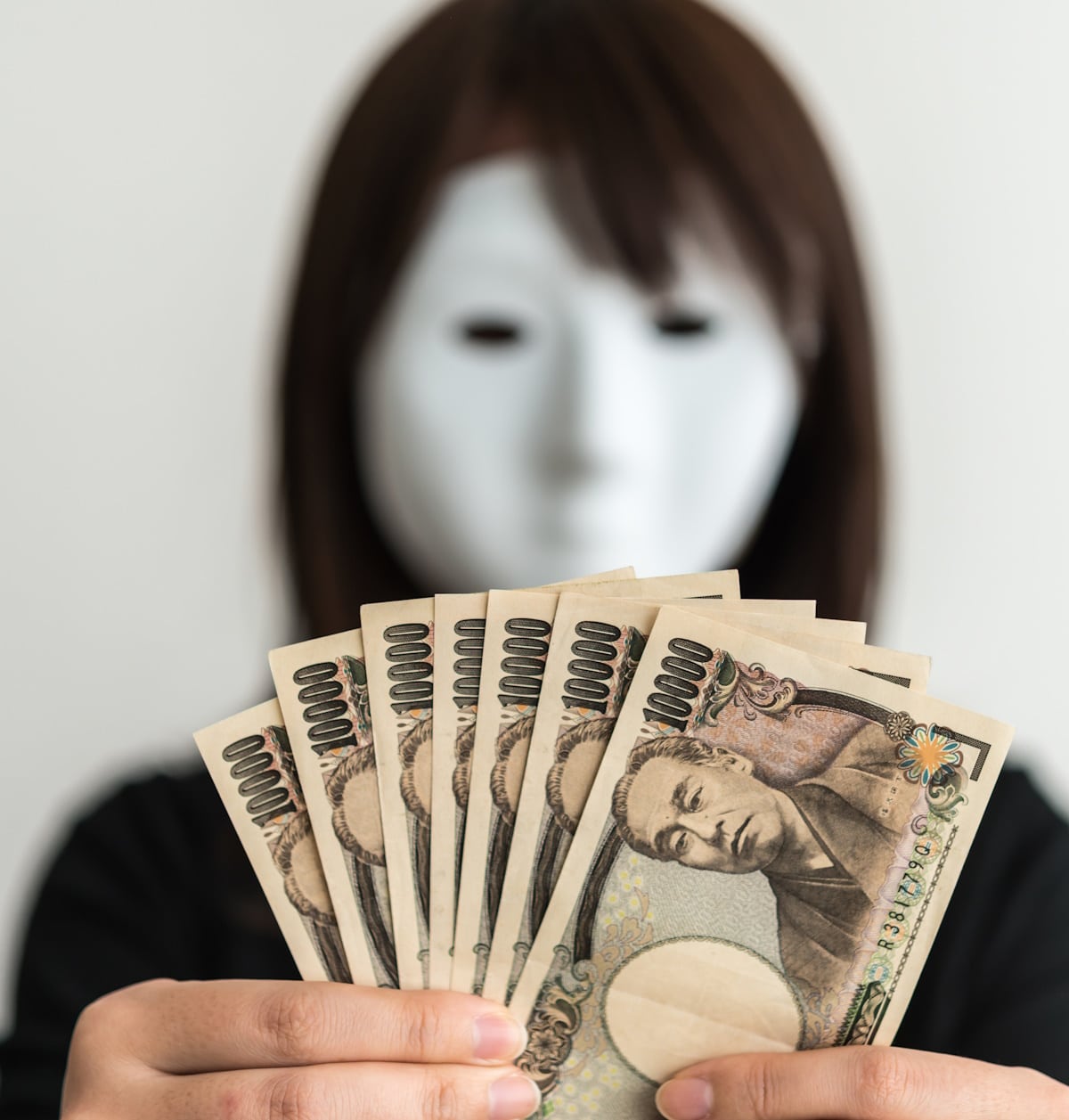 Woman in mask holding yen - scams targeting tourists in Japan