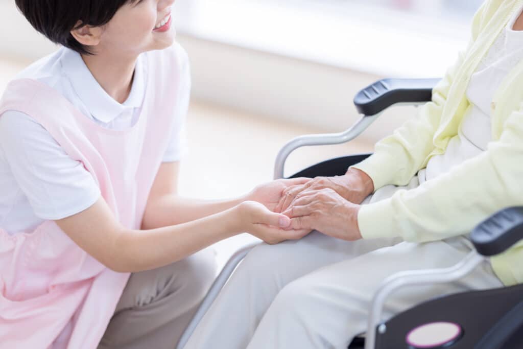 Nursing care - nurse holding the hands of a woman in a wheelchair