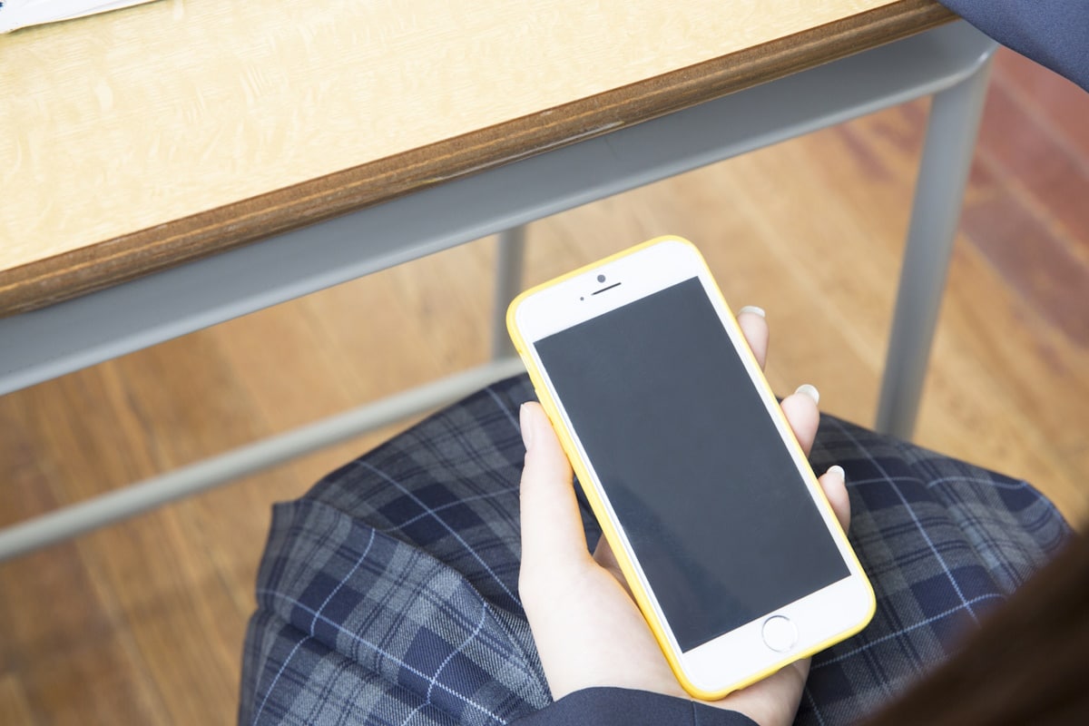 Young schoolgirl holding smartphone