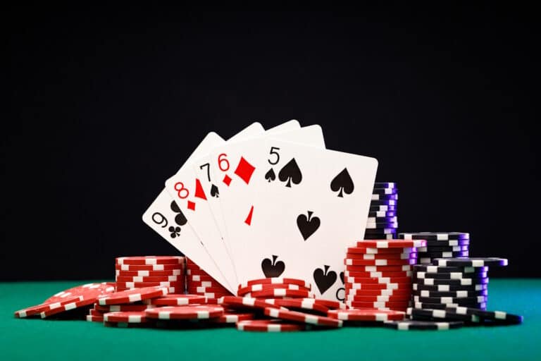 Poker chips and playing cards on black background close up