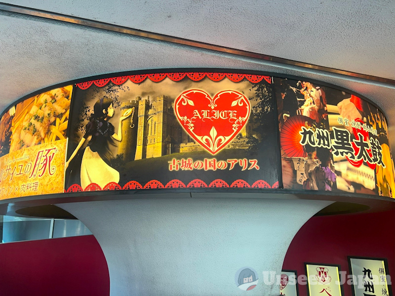 Old Castle Alice - outside showing banner of a young woman on a black and blue blouse and white skirt looking at a pocketwatch with a castle in the background. A heart on the right says "ALICE" and the name of the store is written below in Japanese (古城の国のアリス)