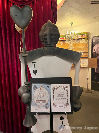 Old Castle Alice - statue of a knight whose body is made of the seven of spaces playing card with the restaurant's meny set before him