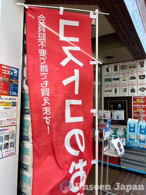 A banner at E-Cost, a Costco resale shop in Hiroo, Minato City, has a banner reading, "Anyone can buy - no membership required!"