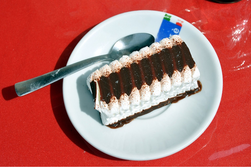 A Viennetta on a white plate with a spoon off to the left and the plate resting on a red tablecloth