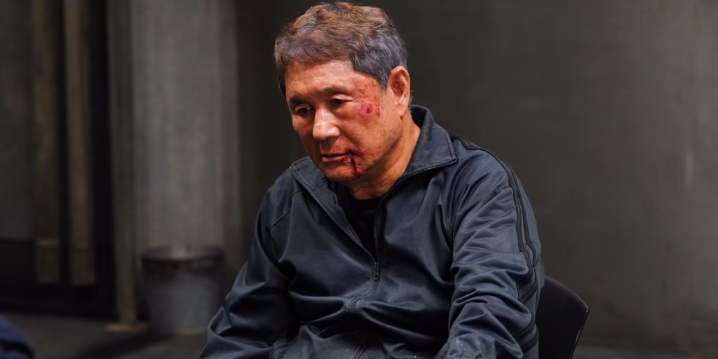 Kitano Takeshi in Broken Rage, bloodied and waring a dark tracksuit.