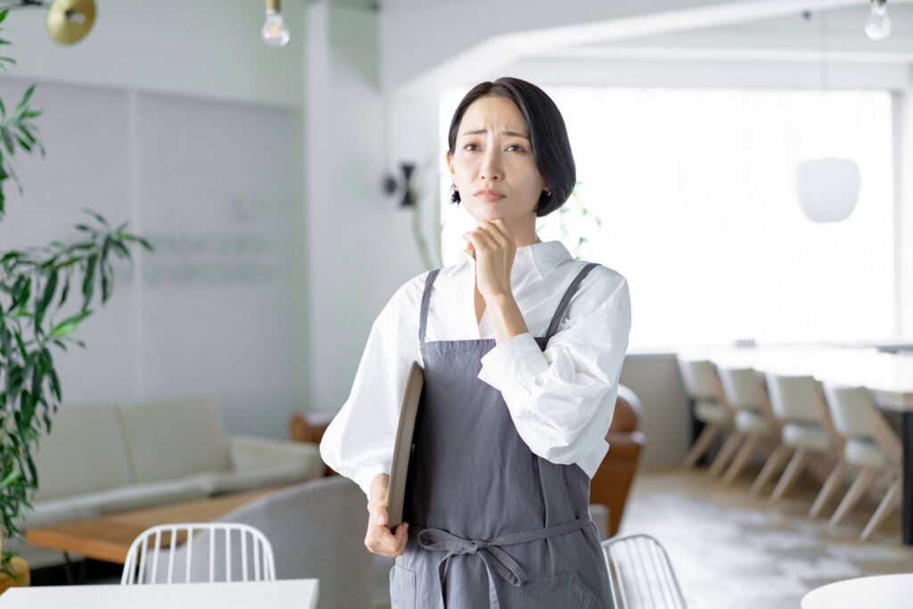 Female restaurant server holding tray and looking worried