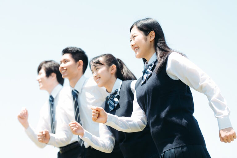 Four high school students running towards the left, staggered from left to right with two boys in back and two girls in front