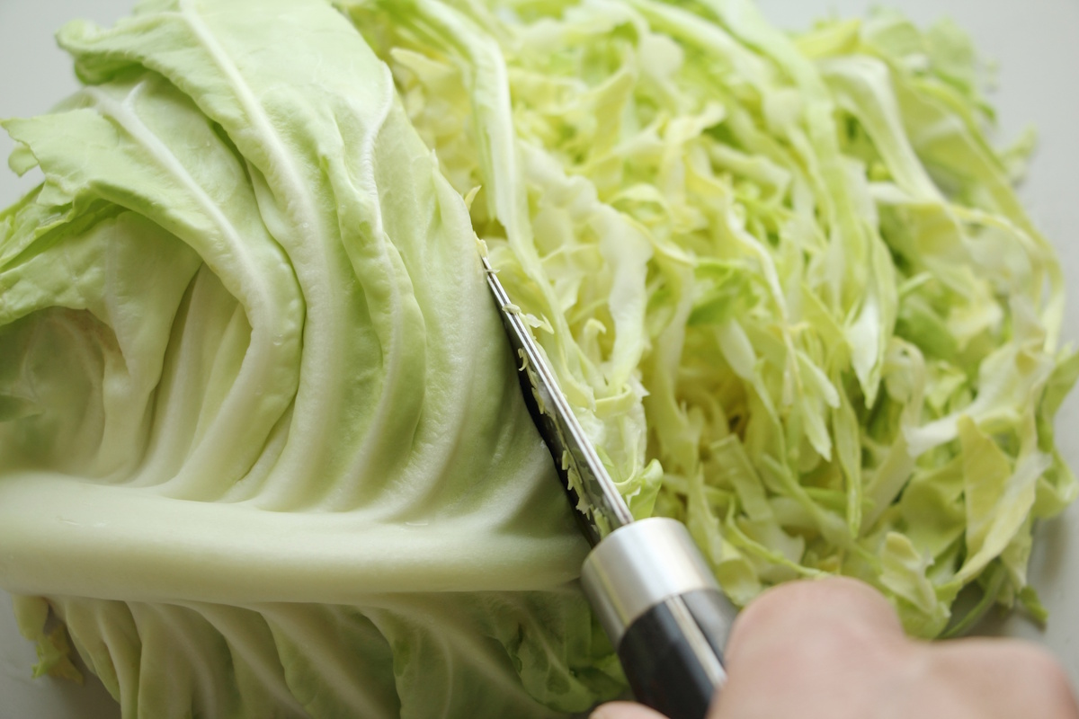 A knife slicing into cabbage