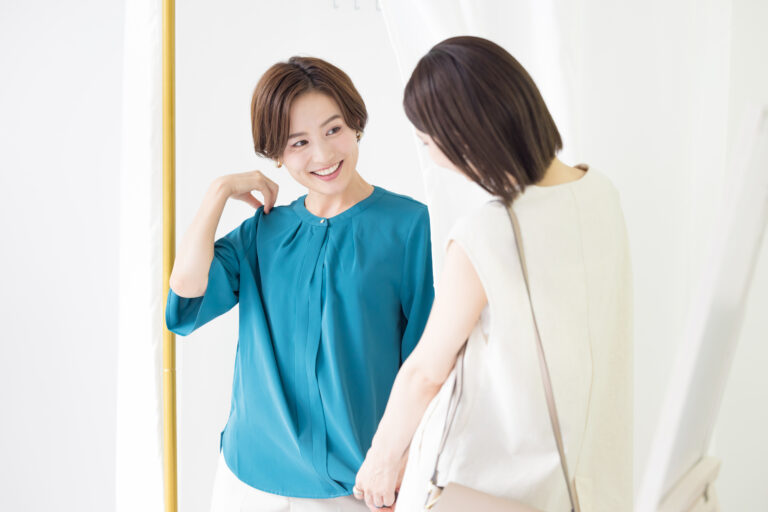 Woman trying on new blouse steps out of a changing room to show it to her friend