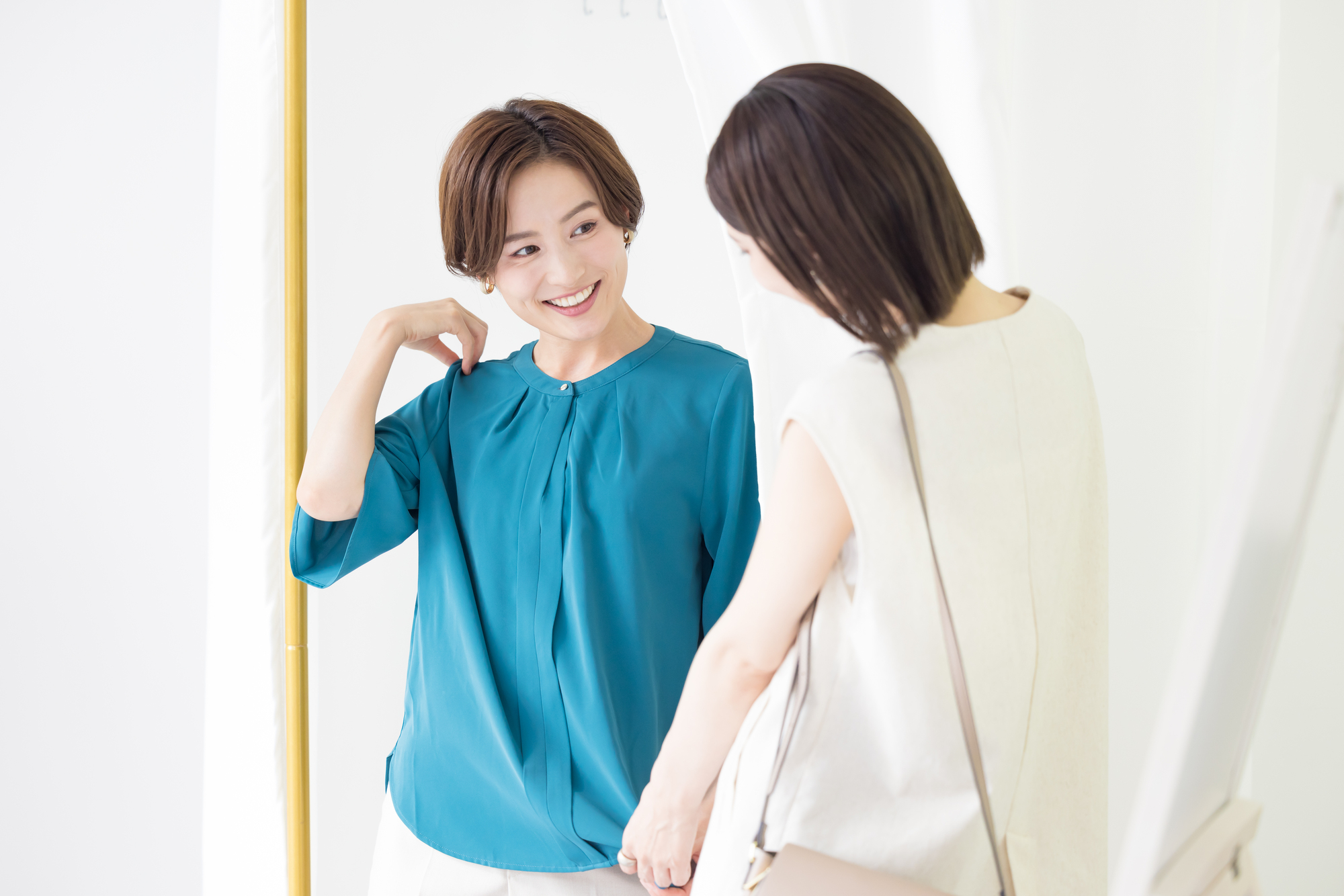 Woman trying on new blouse steps out of a changing room to show it to her friend