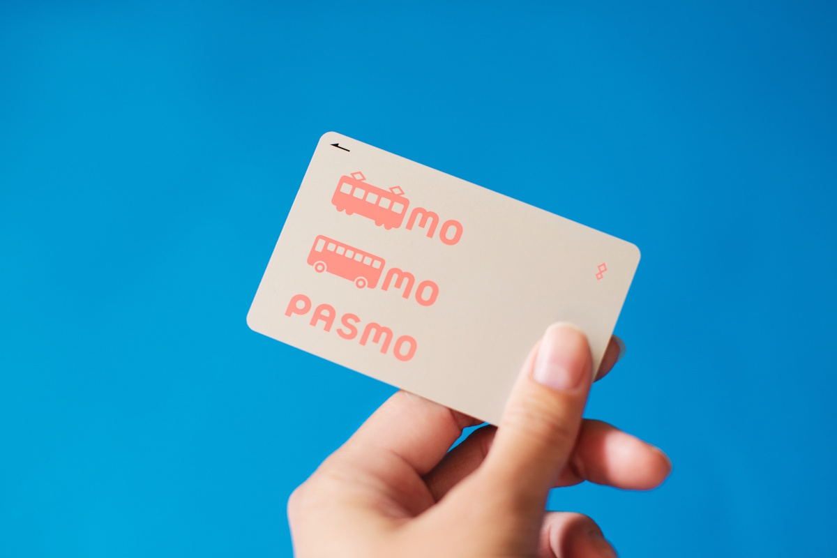 PASMO card - picture of a hand holding a silver PASMO card with pink text against a blue background