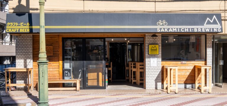 The exterior of Sakamiachi Breweing, showing wooden tables and an open sliding glass door.