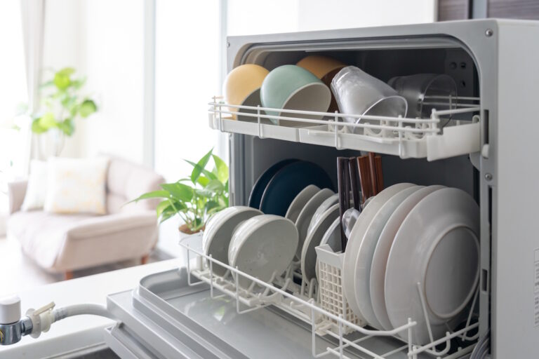 Picture of an open dishwasher with a nice living room visible in the background