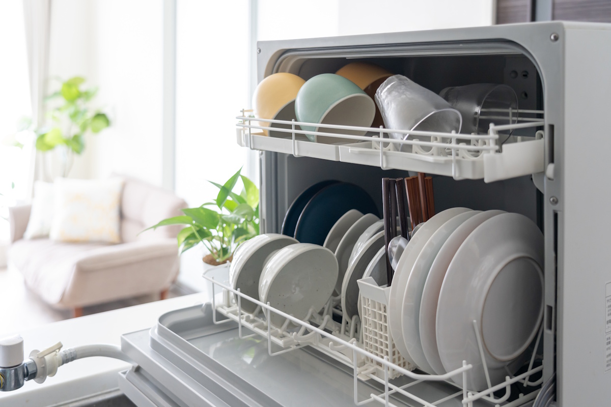 Picture of an open dishwasher with a nice living room visible in the background