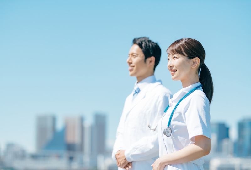 Male and female health care professionals standing side by side against the backdrop of a city skyline